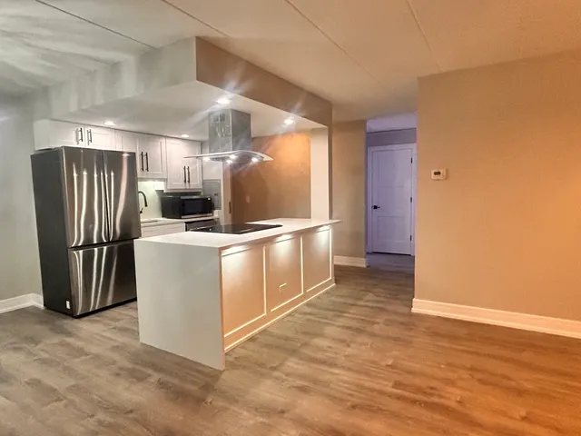 a kitchen with stainless steel appliances a refrigerator and a wooden floor