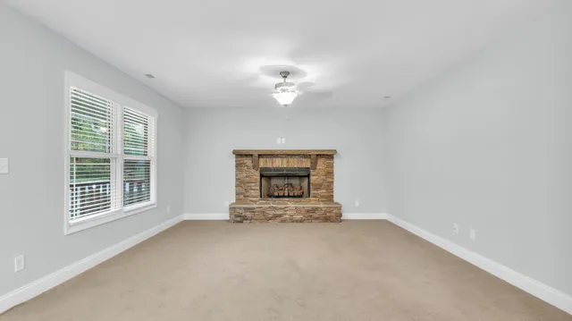 an empty room with chandelier fan and windows