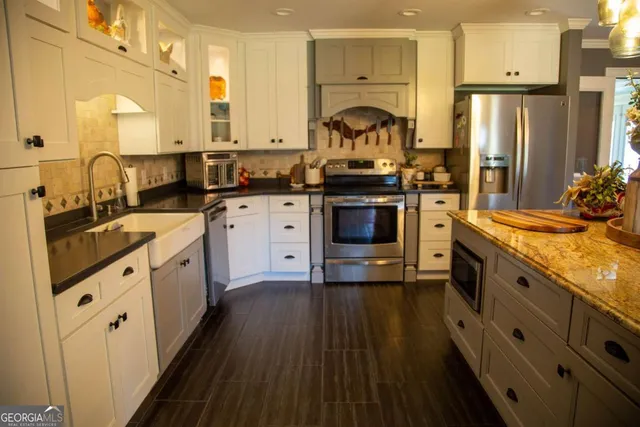 a kitchen with stainless steel appliances a stove a sink dishwasher a refrigerator and a stove with wooden floors