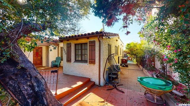 a view of a patio with table and chairs potted plants and a large tree