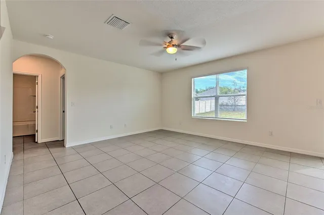 an empty room with chandelier fan and windows