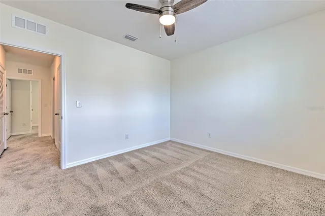 an empty room with a ceiling fan and window