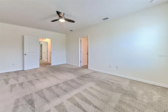 an empty room with ceiling fan and window