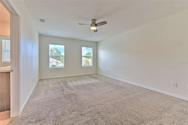 an empty room with windows and ceiling fan