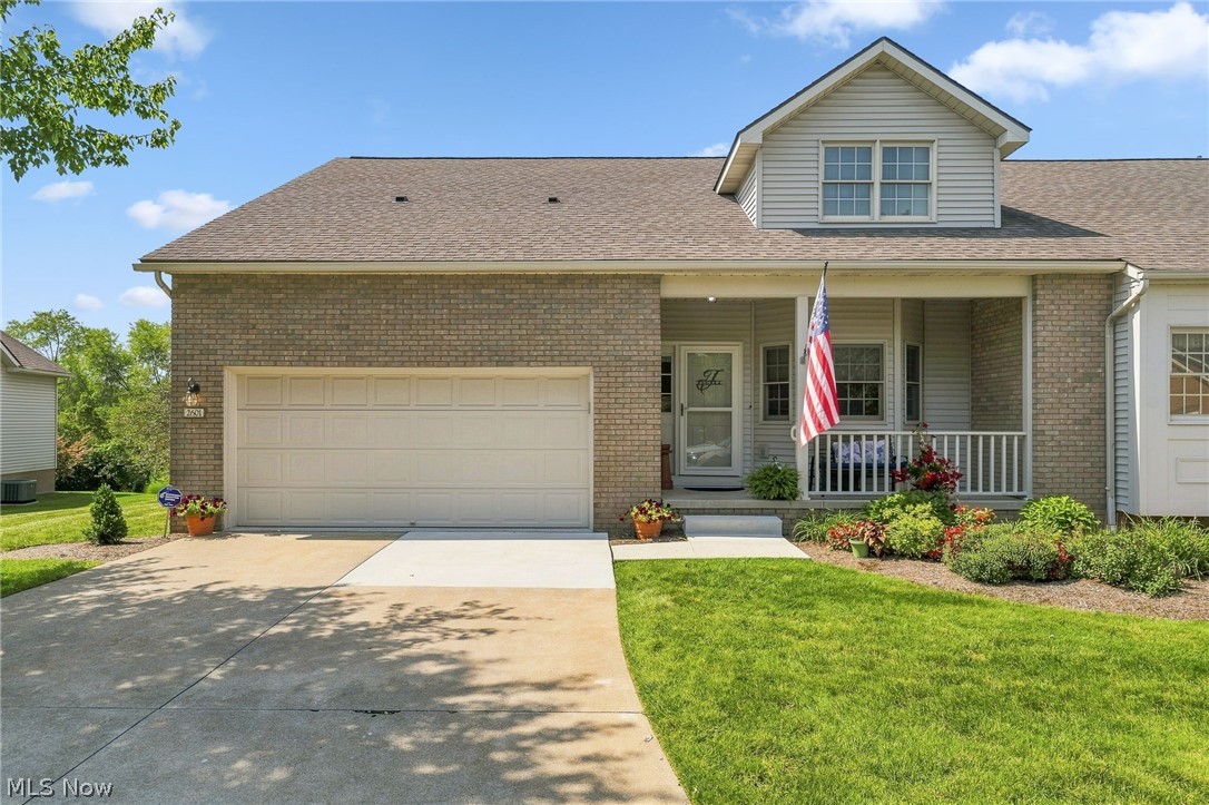 2601 Charing Cross Road Northwest Canton, OH 44708 - Photo 1 of 49 Brick facade with a covered front porch featuring white railing, an integrated garage, dormer window, and mature landscaping