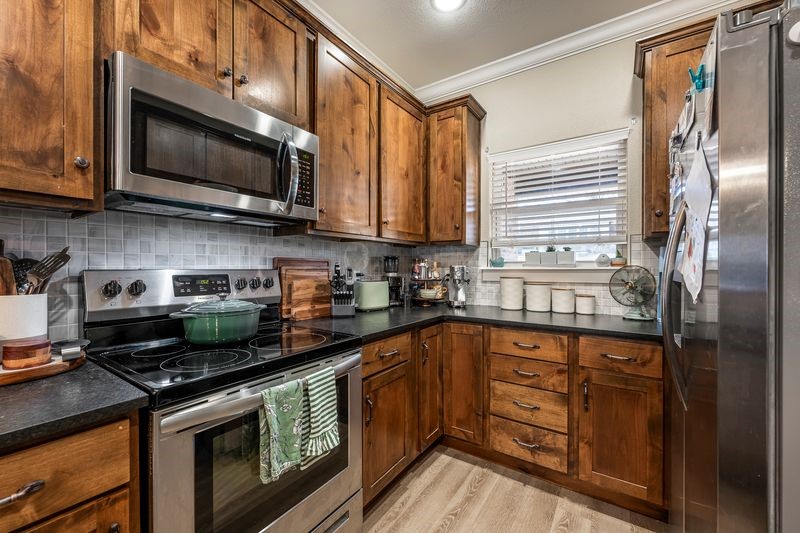 10859 Danny Bryan Road Prairie Grove, AR 72753 - Photo 6 of 30 Kitchen with stainless steel appliances, granite countertops, crown molding, decorative backsplash, and custom cabinetry.