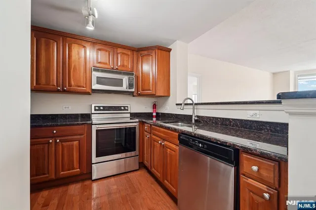 a kitchen with stainless steel appliances granite countertop a stove a sink and a microwave