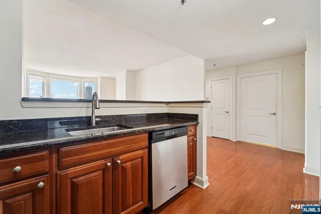 a kitchen with granite countertop a sink cabinets and wooden floor