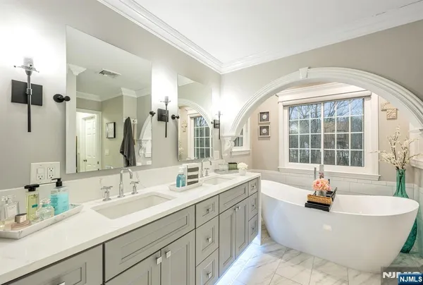 a bathroom with a double vanity sink large mirror and a bathtub