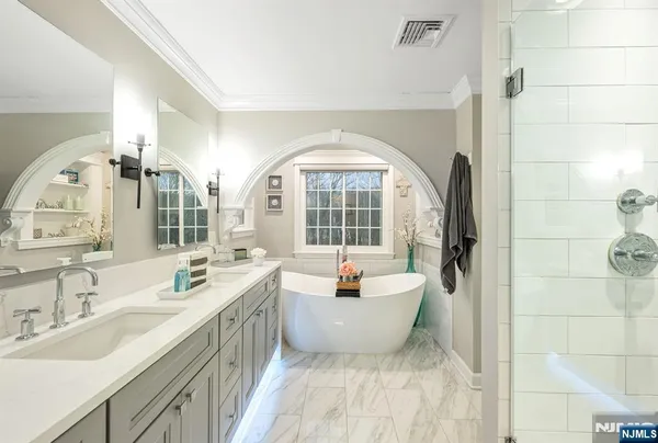 a spacious bathroom with a double vanity sink a mirror and a bathtub