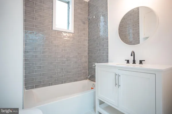 a bathroom with a tub sink and mirror