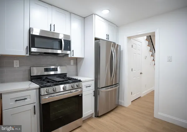 a kitchen with stainless steel appliances white cabinets a stove a microwave and a refrigerator