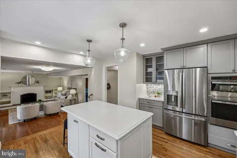 a kitchen with a refrigerator a sink dishwasher and white cabinets with wooden floor