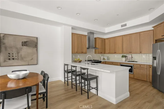 a kitchen with stainless steel appliances granite countertop a table chairs sink and cabinets