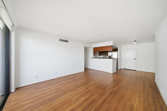 a view of a big room with wooden floor and windows
