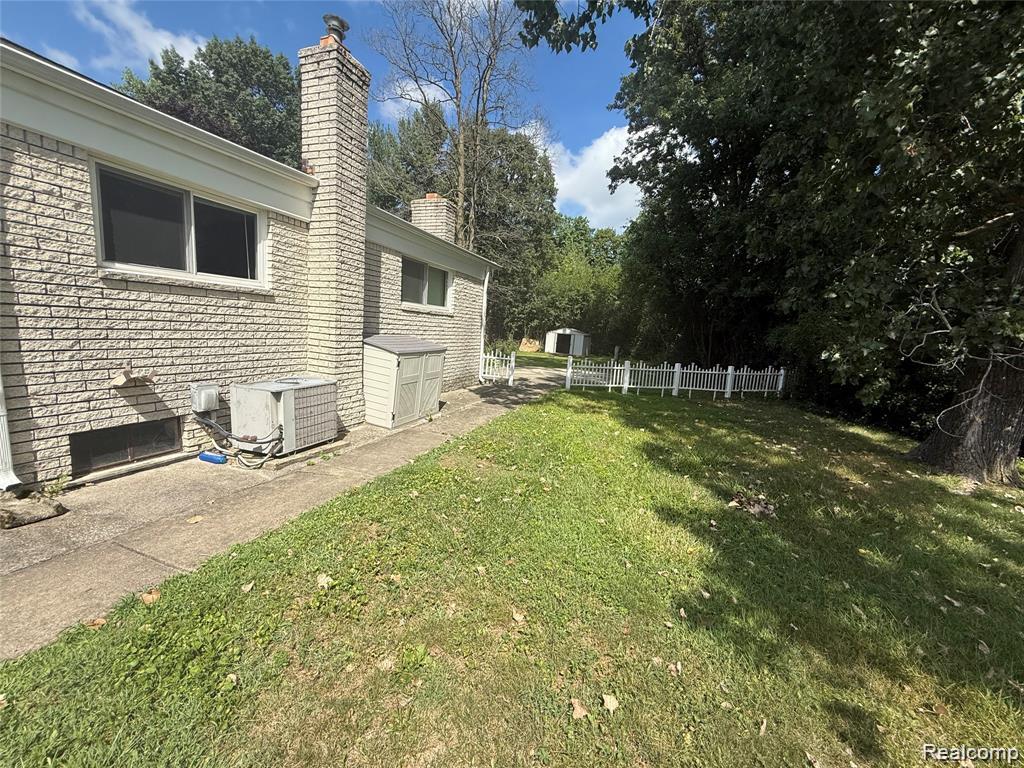 43038 Hanford Road Canton, MI 48187 - Photo 3 of 36 Expansive lawn with mature trees, featuring a white picket fence and an exterior storage shed