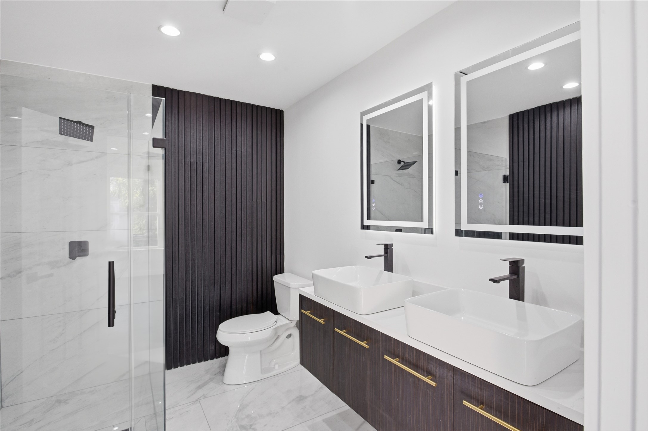 4516 Werner Street Houston, TX 77022 - Photo 2 of 28 Beautifully updated bathroom with dual vanities, a walk-in shower, and a bold black accent wall that adds a modern, designer touch.