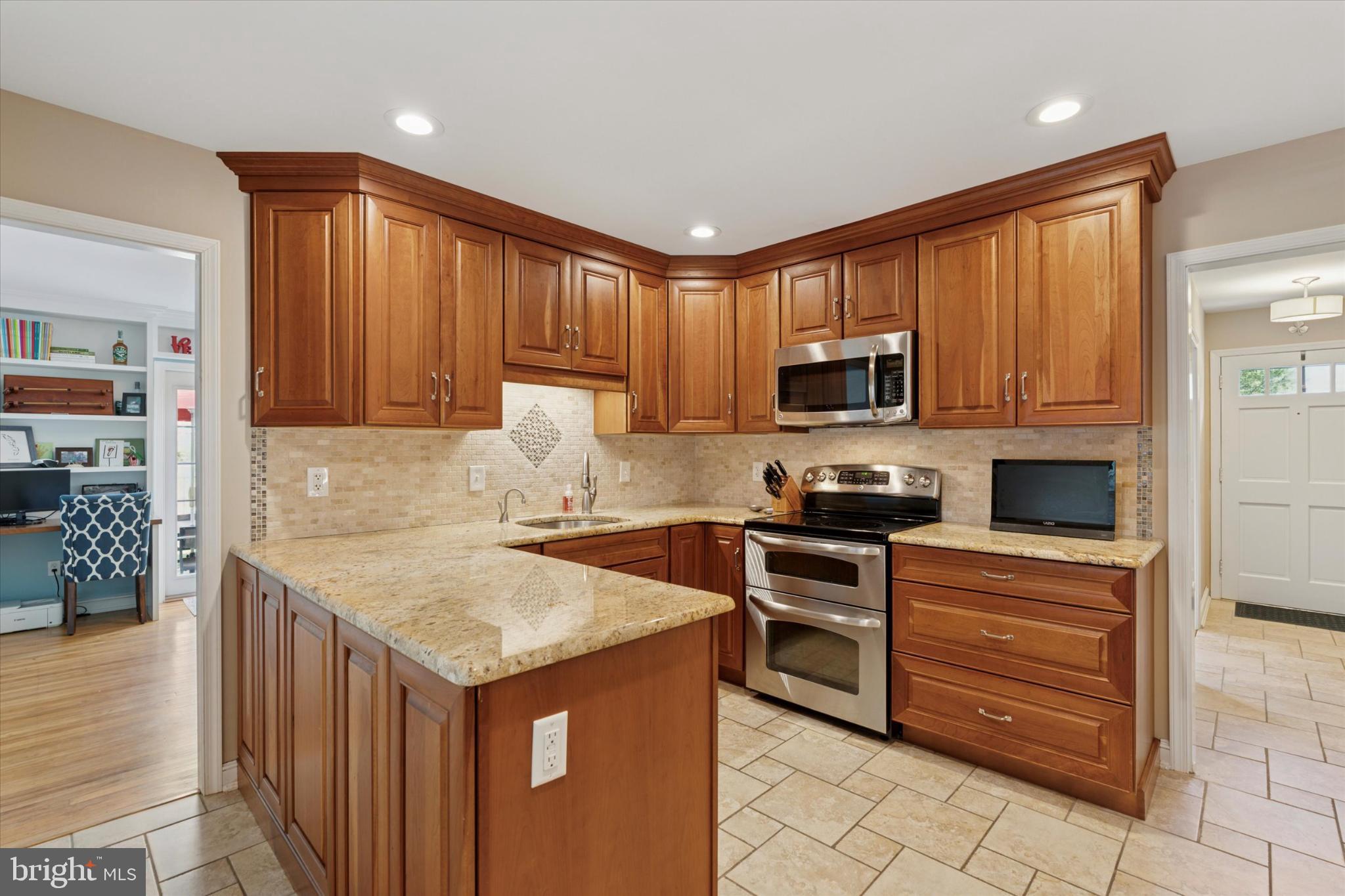 101 Rockland Road Havertown, PA 19083 - Photo 5 of 35 a kitchen with stainless steel appliances granite countertop a stove top oven a sink dishwasher and a refrigerator with wooden cabinets