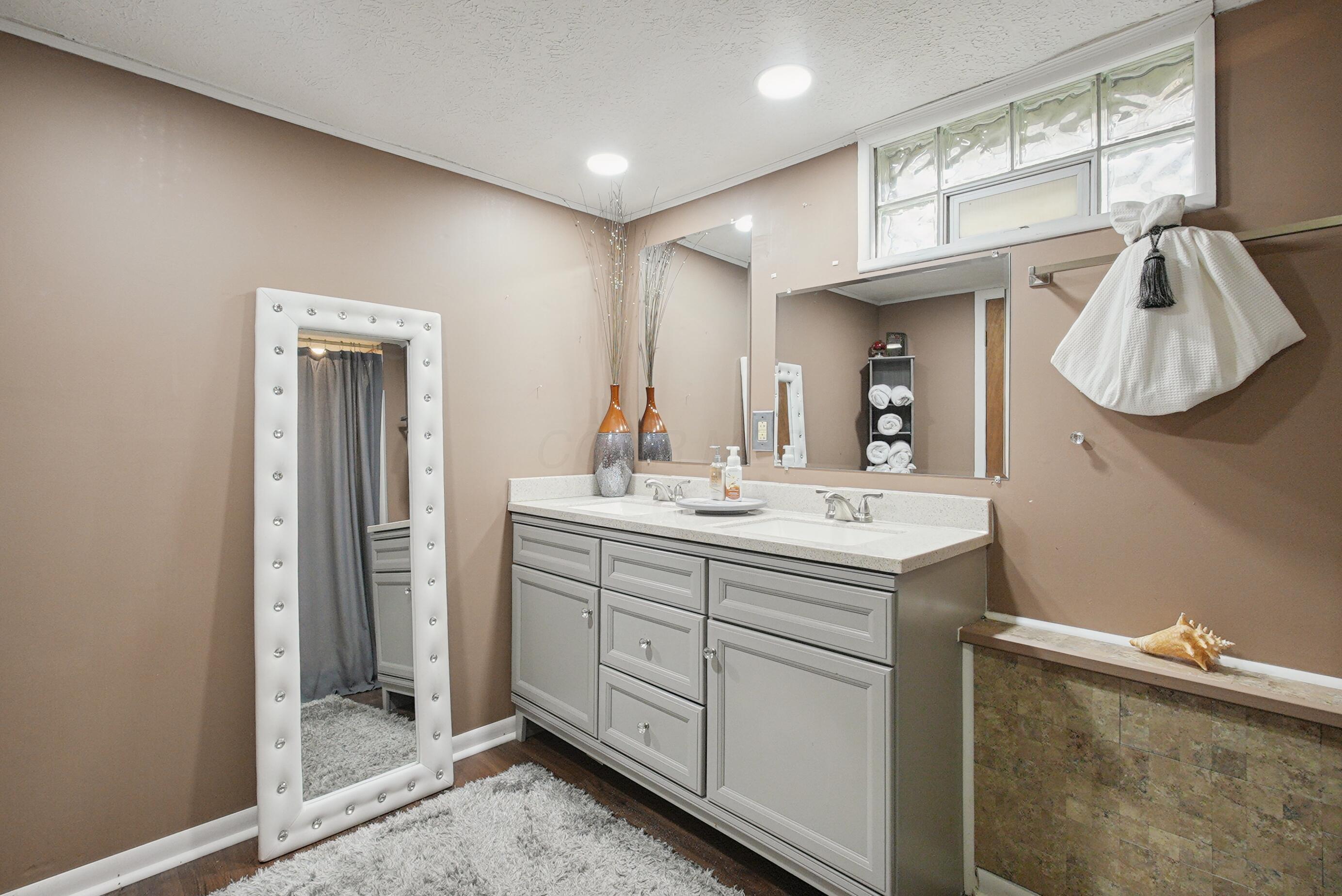 1636 Courtright Road Columbus, OH 43227 - Photo 27 of 35 Basement Bathroom with Double vanity with light gray cabinetry, wall-mounted mirror, recessed lighting, and glass block window