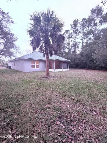 a view of house with yard and trees in the background
