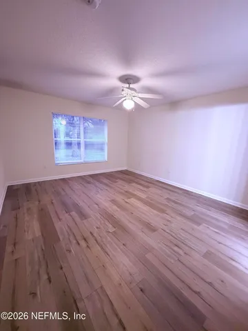a view of empty room with wooden floor and fan
