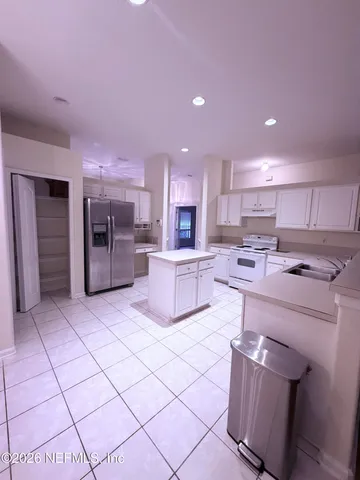 a kitchen with stainless steel appliances kitchen island granite countertop a refrigerator and a sink