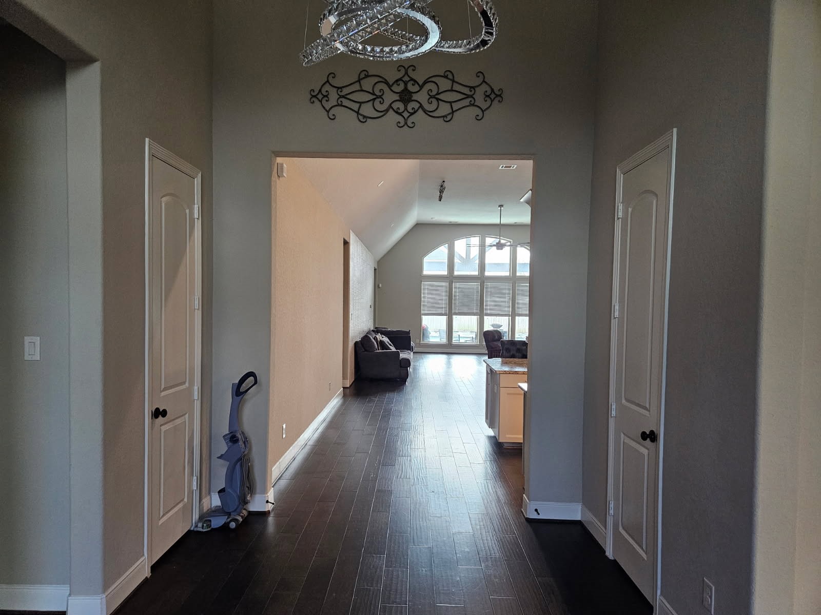 18919 Steep Step Trail Cypress, TX 77433 - Photo 3 of 12 This photo shows a bright hallway with dark wood flooring leading to a spacious living area. The space features high ceilings, large windows, and modern fixtures, providing an open and airy feel.