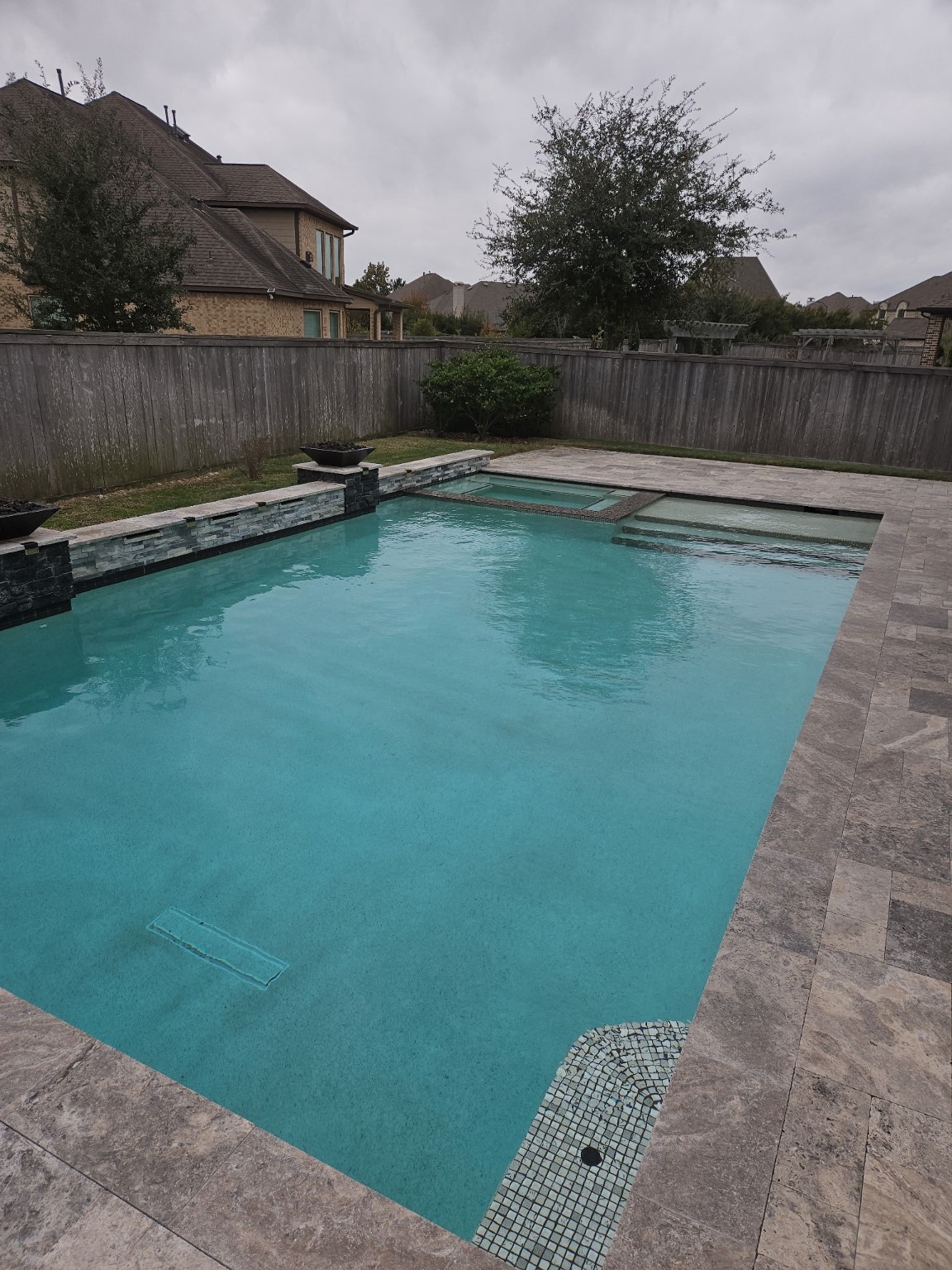 18919 Steep Step Trail Cypress, TX 77433 - Photo 4 of 12 This photo showcases a spacious backyard pool with a stone deck and integrated spa. It's enclosed by a wooden fence, providing privacy and a serene atmosphere, ideal for relaxation and entertainment.