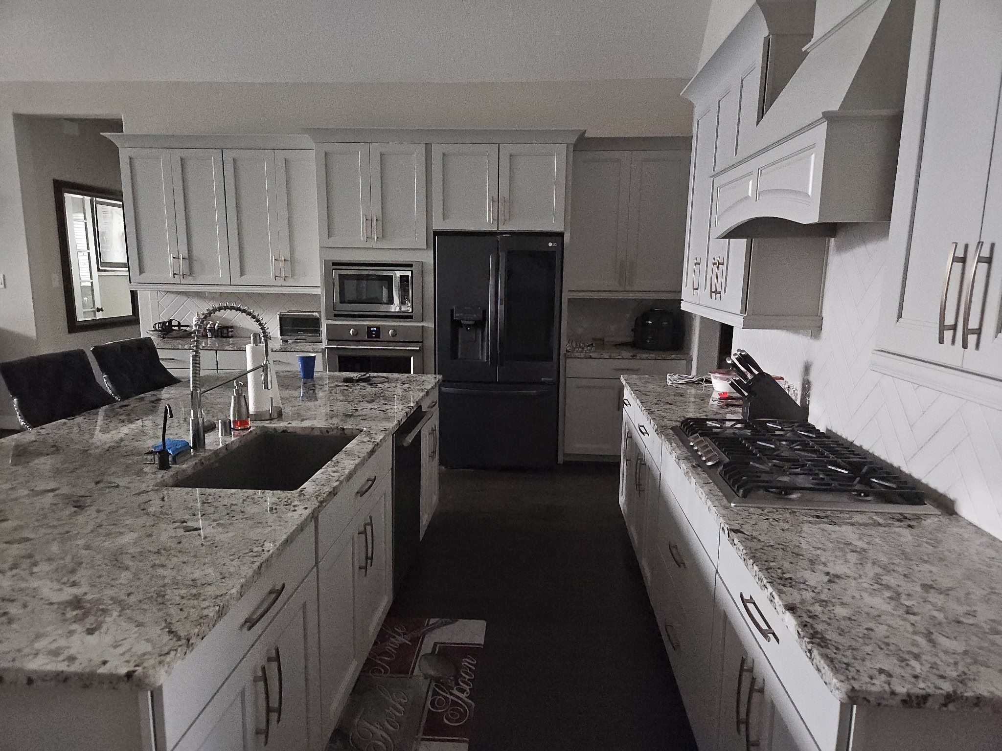 18919 Steep Step Trail Cypress, TX 77433 - Photo 8 of 12 This modern kitchen features sleek white cabinetry, granite countertops, and stainless steel appliances, including a built-in oven and a large refrigerator. The island offers ample workspace and seating, complemented by a stylish sink and faucet.