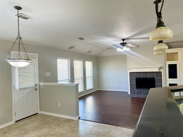 a view of a livingroom with a fireplace a ceiling fan and windows