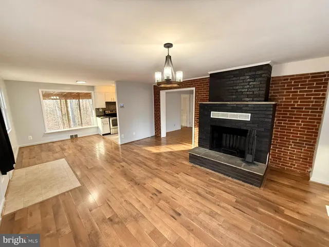 a living room with stainless steel appliances wooden floor and a fireplace