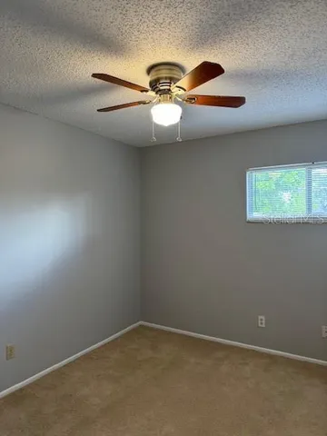 an empty room with a bathroom and a chandelier fan