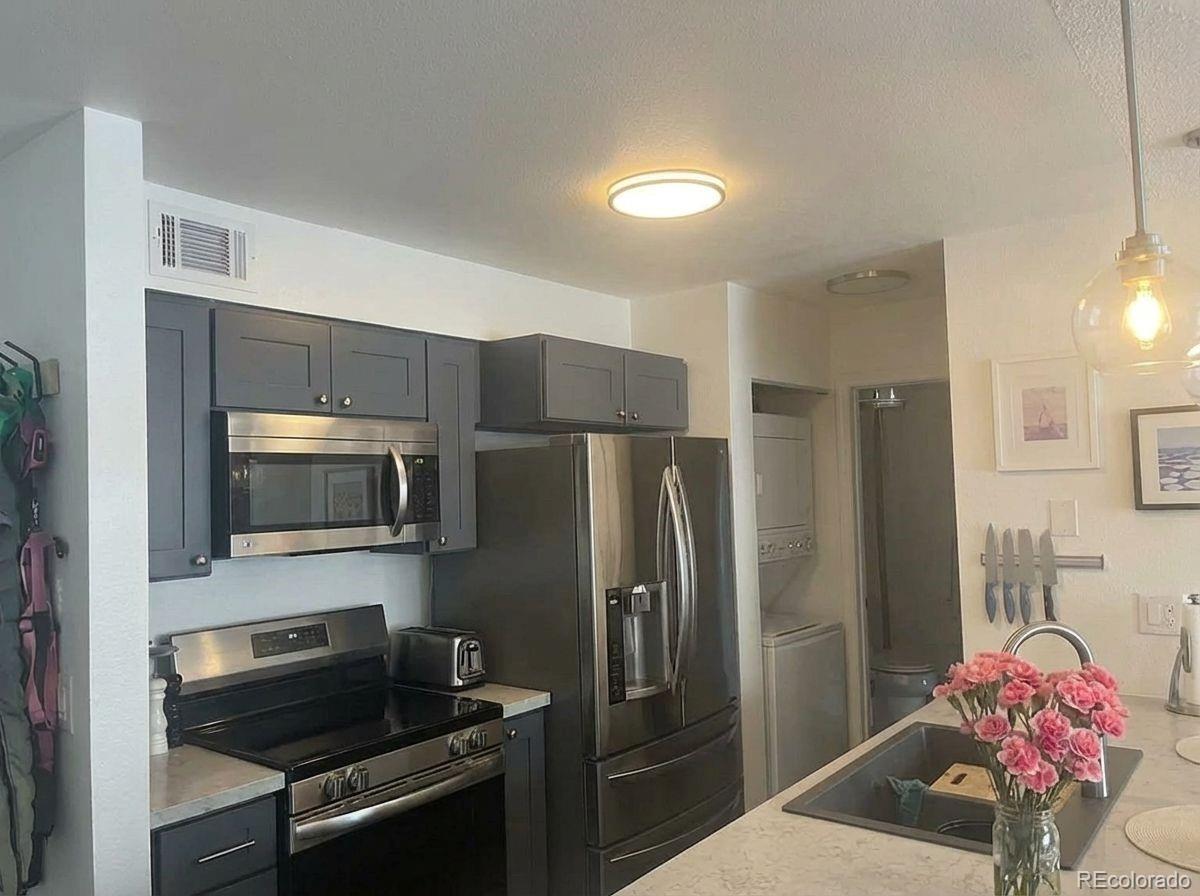 2575 South Syracuse Way, Unit D103 Denver, CO 80231 - Photo 1 of 10 a kitchen with a refrigerator and a stove top oven