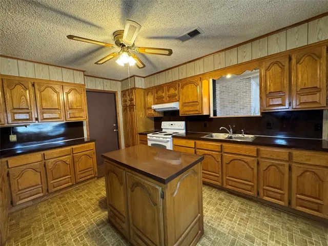 a kitchen with stainless steel appliances granite countertop a sink a stove cabinets counter space and a window
