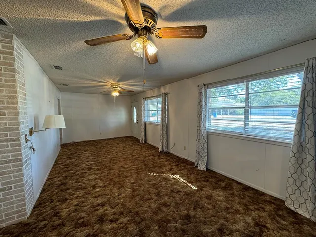 a view of empty room with window and ceiling fan