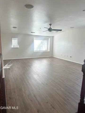 an empty room with wooden floor chandelier and windows