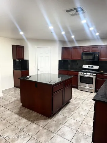 a kitchen with stainless steel appliances kitchen island granite countertop a refrigerator and a stove top oven