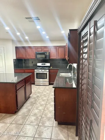 a kitchen with stainless steel appliances granite countertop a stove a sink and a microwave