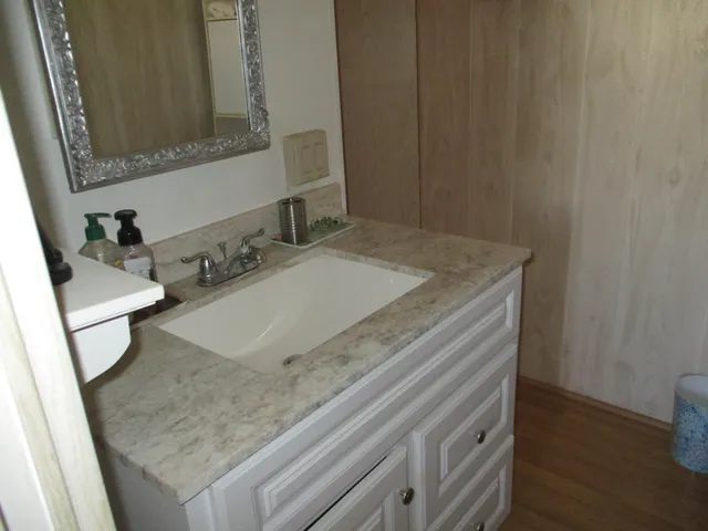 a bathroom with a granite countertop sink and a mirror