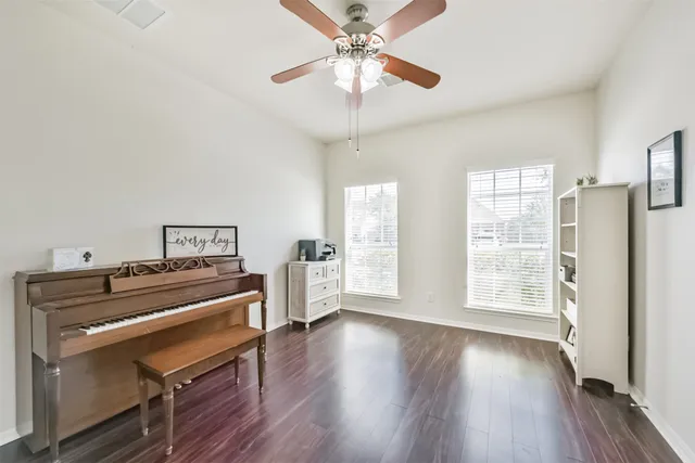 a view of a livingroom with furniture hardwood floor ceiling fan and windows