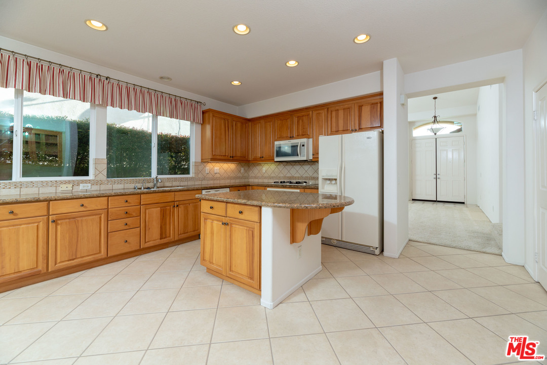 6837 Raspberry Court Eastvale, CA 92880 - Photo 8 of 41 a kitchen with kitchen island granite countertop a stove a sink and a refrigerator