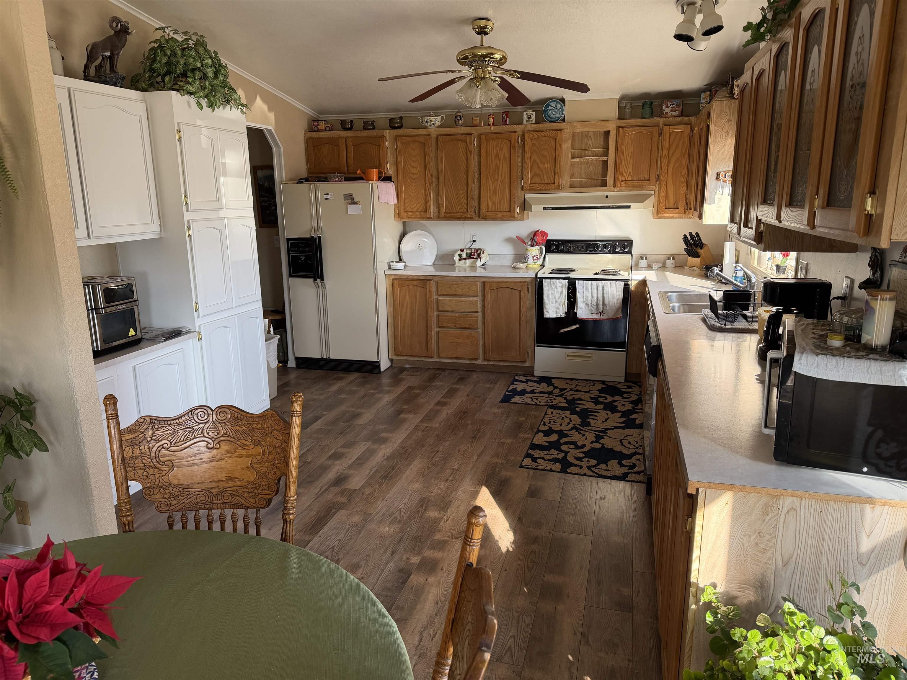 13648 Highway 44 Caldwell, ID 83607 - Photo 5 of 8 Kitchen featuring light countertops, white appliances, dark wood-style flooring, under cabinet range hood, and a ceiling fan