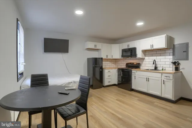 a kitchen with stainless steel appliances a stove a refrigerator a microwave a dining table and chairs