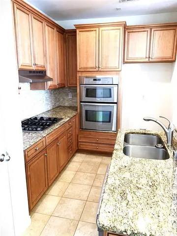 a kitchen with granite countertop a stove a sink and a microwave