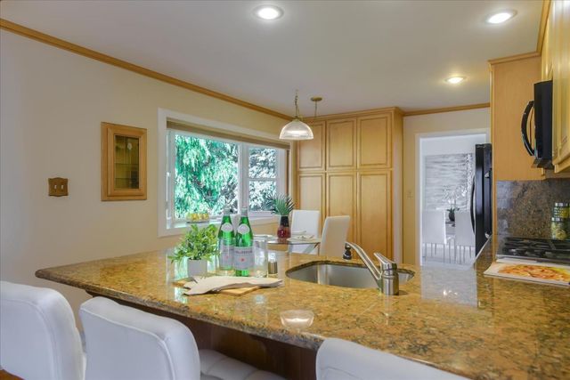 a kitchen with stainless steel appliances granite countertop a sink and a refrigerator