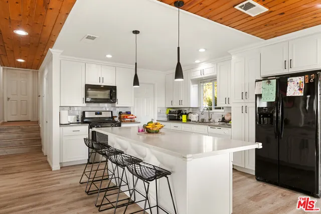 a kitchen with stainless steel appliances a table chairs refrigerator and microwave