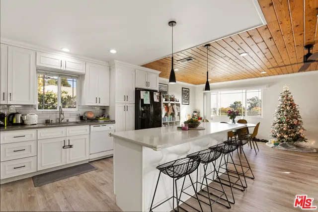 a kitchen with stainless steel appliances kitchen island granite countertop a table chairs and a wooden floor