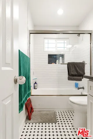 a bathroom with a sink a toilet a window and shower