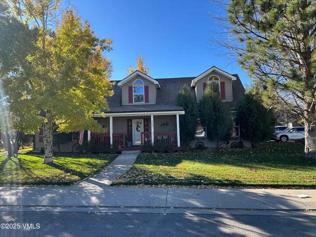 a view of a big yard in front of a brick house with large windows