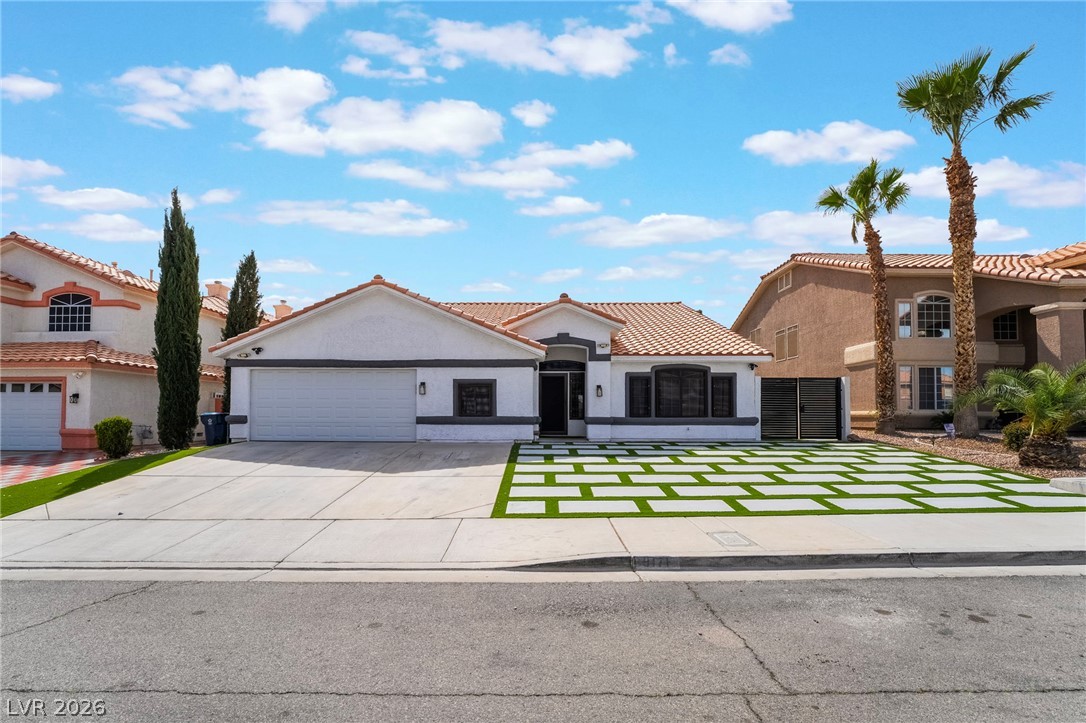9171 West Viking Road Las Vegas, NV 89147 - Photo 4 of 43 A well-maintained single-story residence with a modern paver-style driveway, lush palms, and a two-car garage.